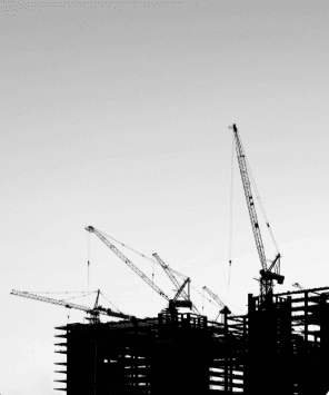 Silhouette of construction site with multiple cranes against a clear sky.