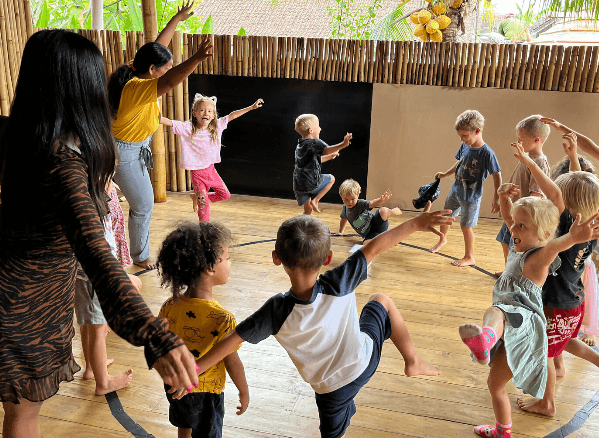 Group of children participating in a dance or movement activity indoors with supervising adults.